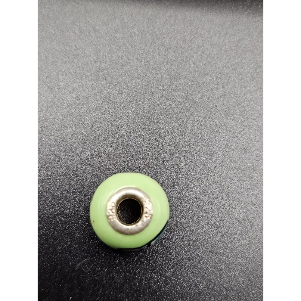 Green bead with silver metal core on a gray background