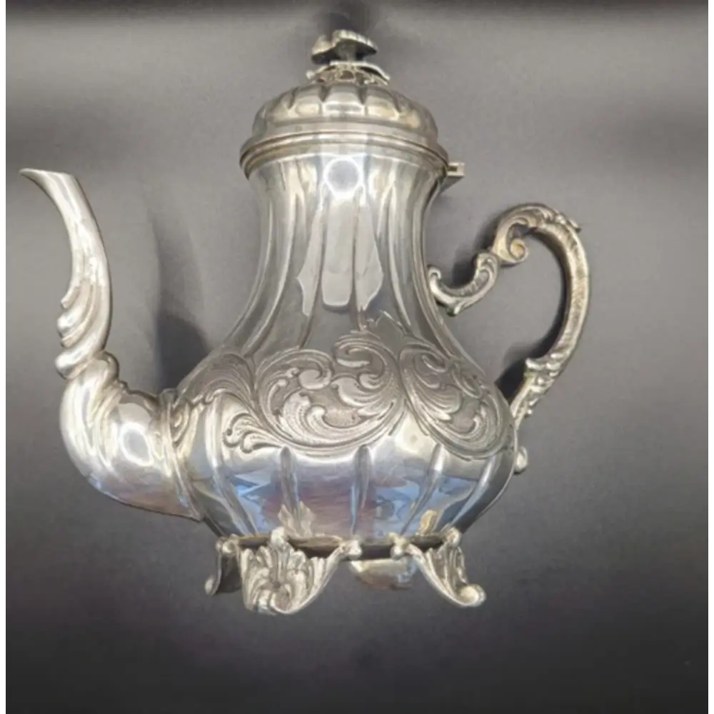 Side view of antique silver tea set showcasing detailed craftsmanship