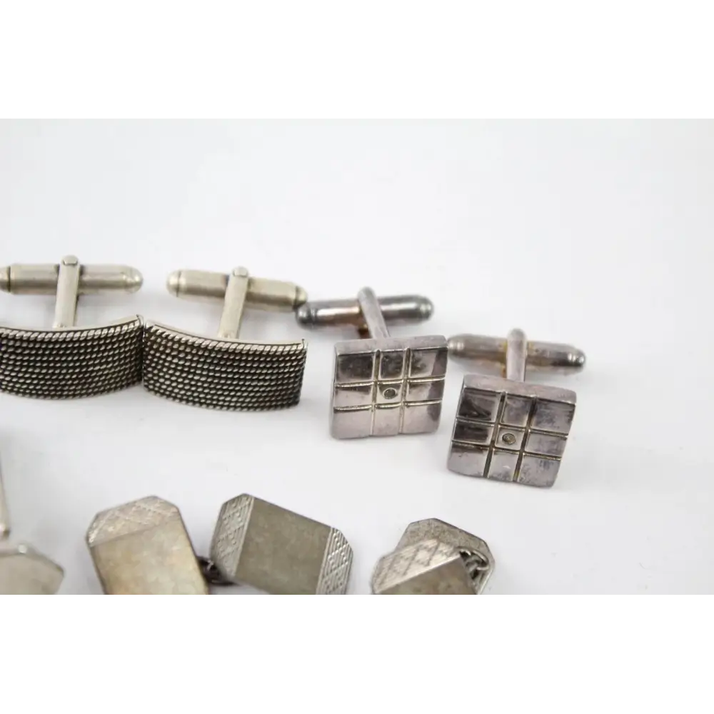 Collection of silver cufflinks on a white background
