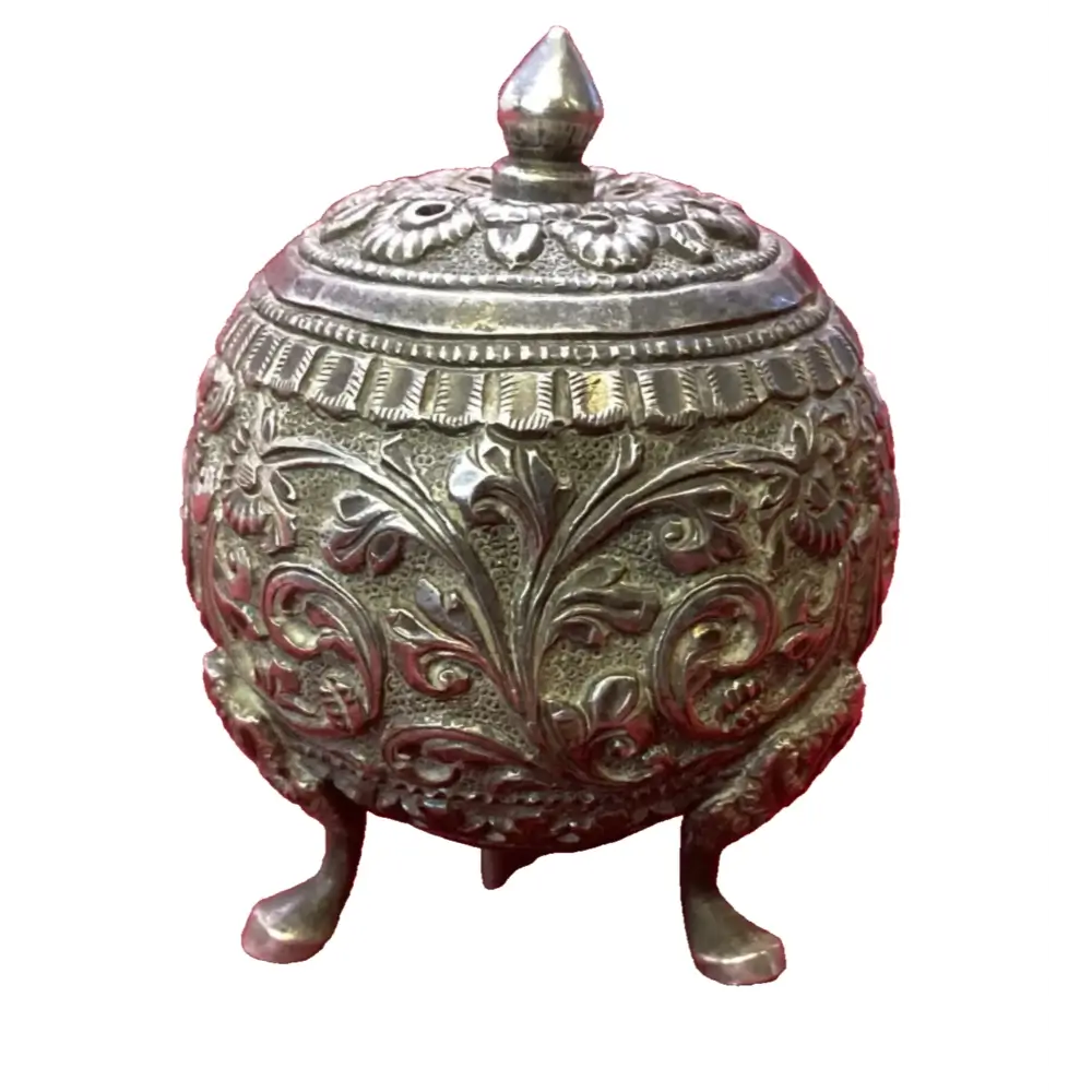Decorative metal container with intricate designs on a white background