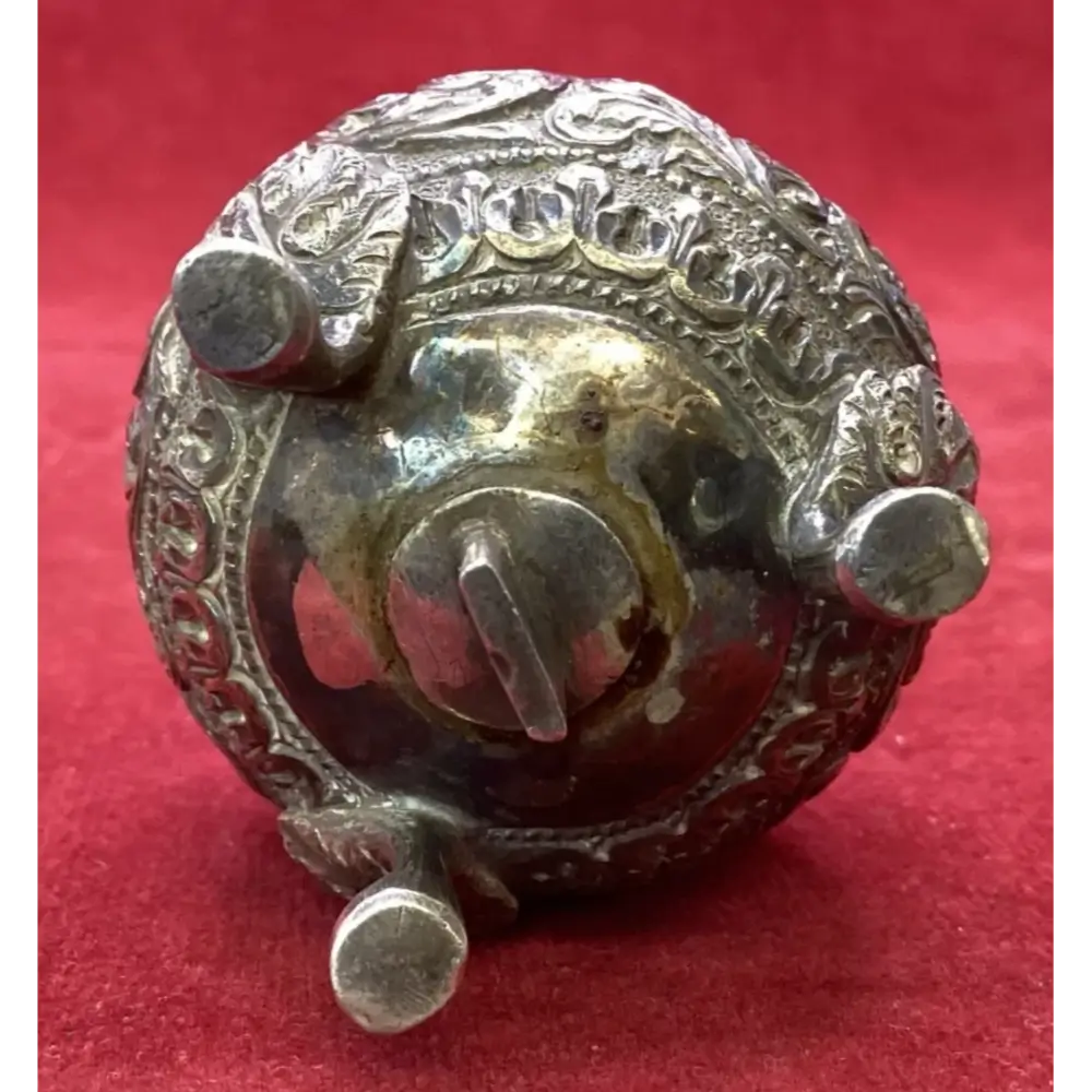 Decorative metal object with engraved design on a red background