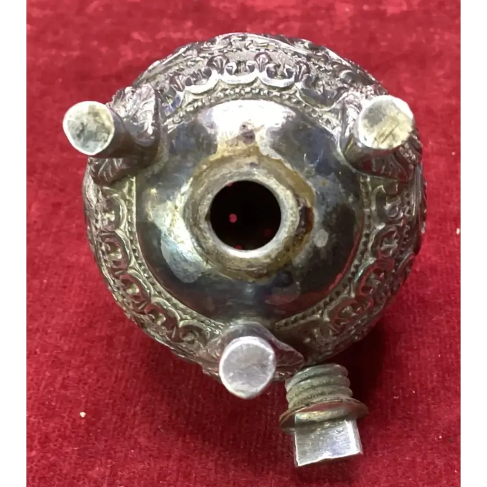 Decorative metal object with intricate designs on a red background