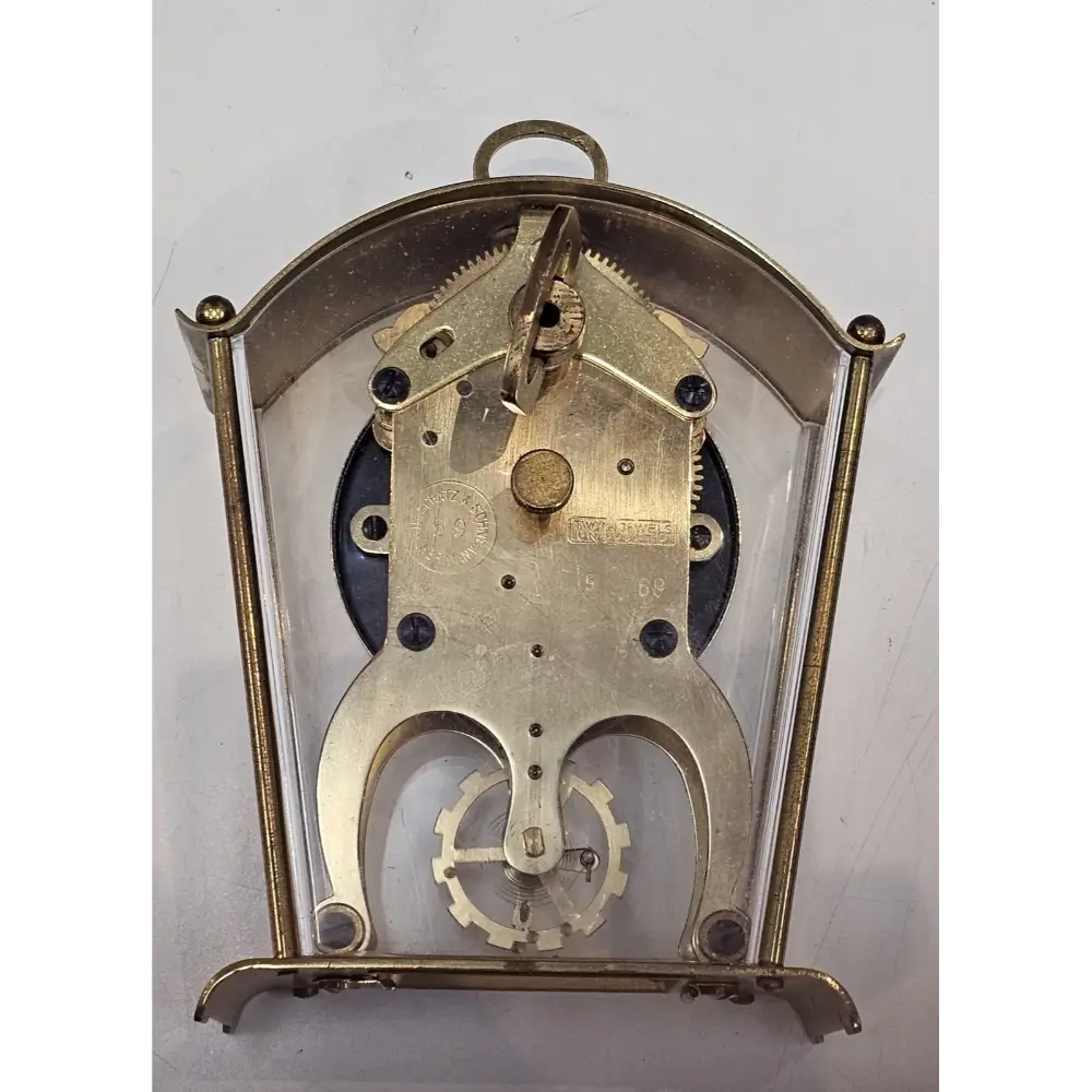 Mechanical clock movement with brass casing on a white background