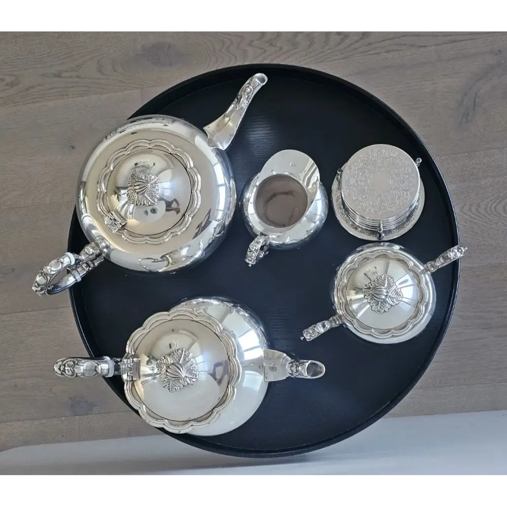 Set of silver teapots on a black tray