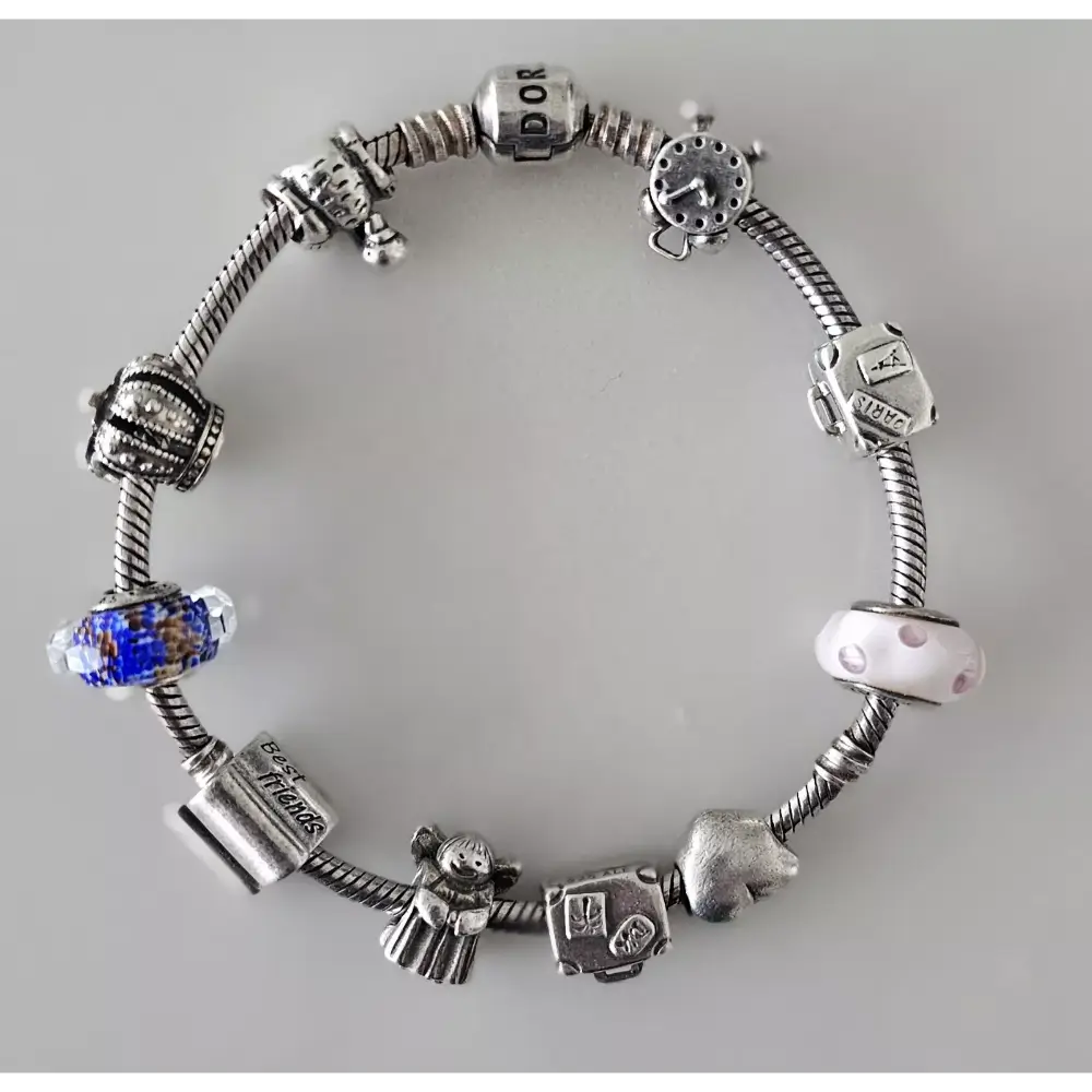 Silver charm bracelet with various charms on a gray background