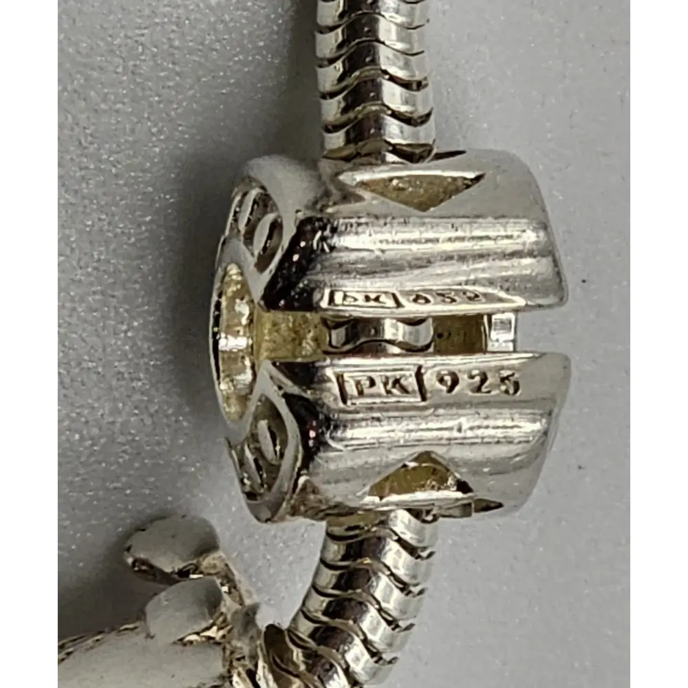 Close-up of a silver charm with 'PK 1923' engraving