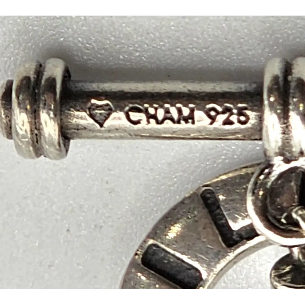 Close-up of a silver charm with 'Gian' and '925' stamp on a white background