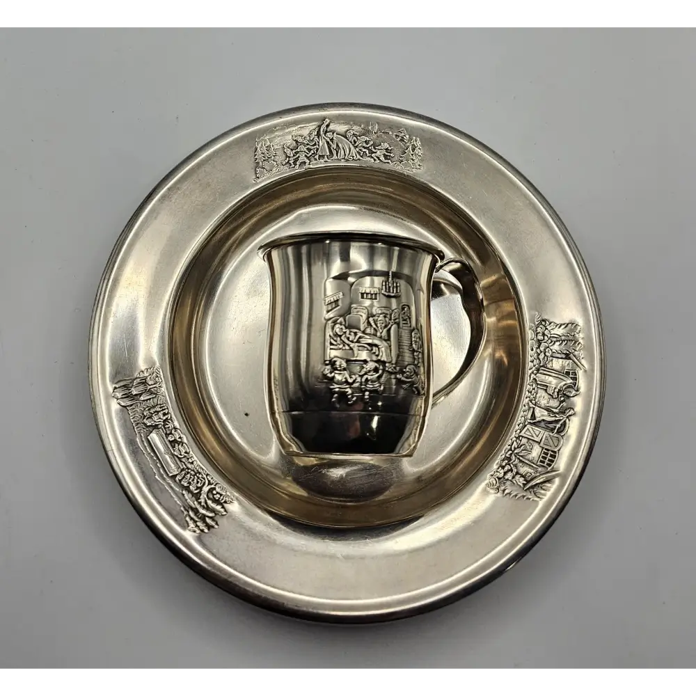 Silver cup and saucer with intricate designs on a gray background