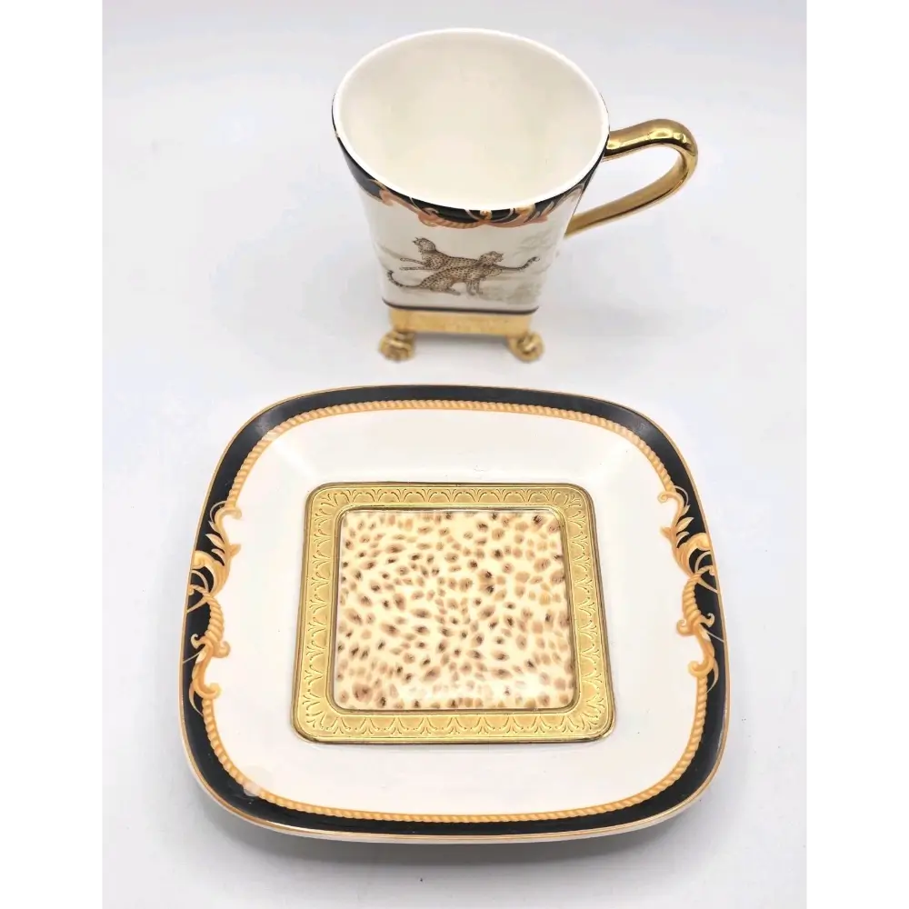 Ceramic cup and saucer with gold and black detailing on a white background