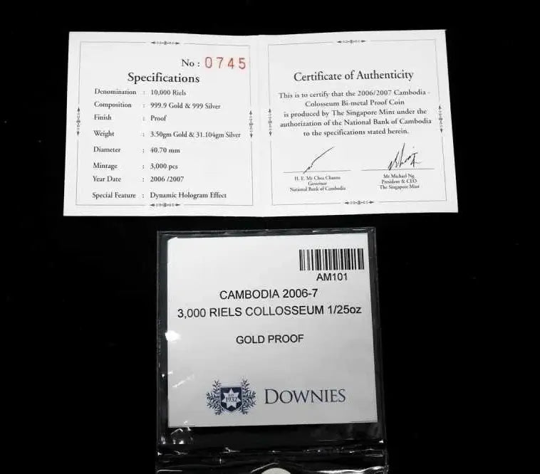 A gold proof collectible coin from Cambodia, sealed in a Downies protective plastic bag, displayed below its authenticity certificate and specifications card on a black background.