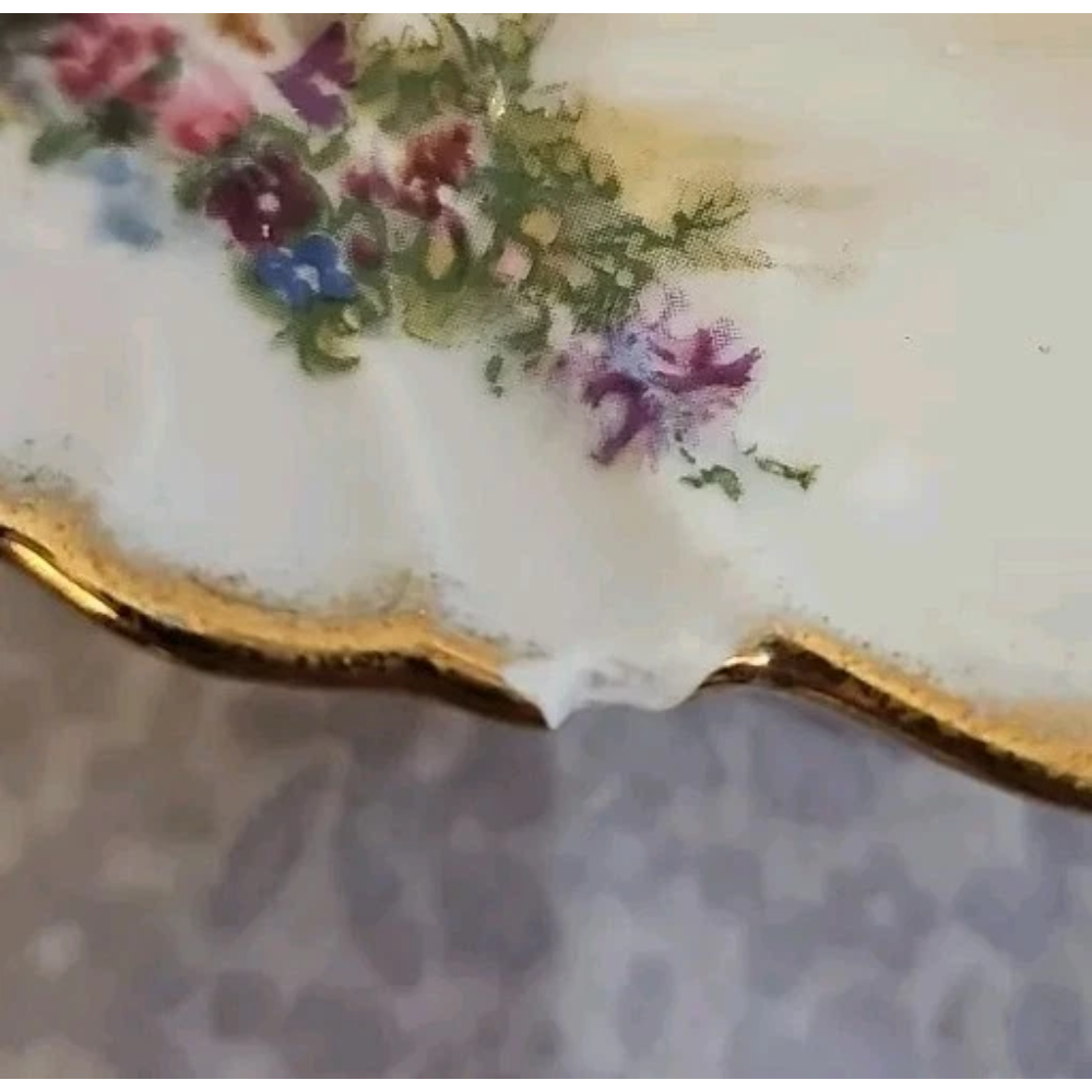 Decorative ceramic plate with floral design and gold rim on a textured surface