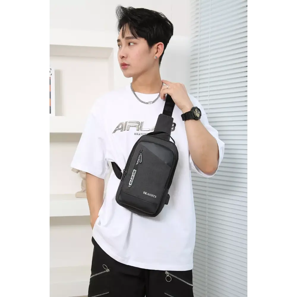 Person wearing a white t-shirt and holding a black sling bag