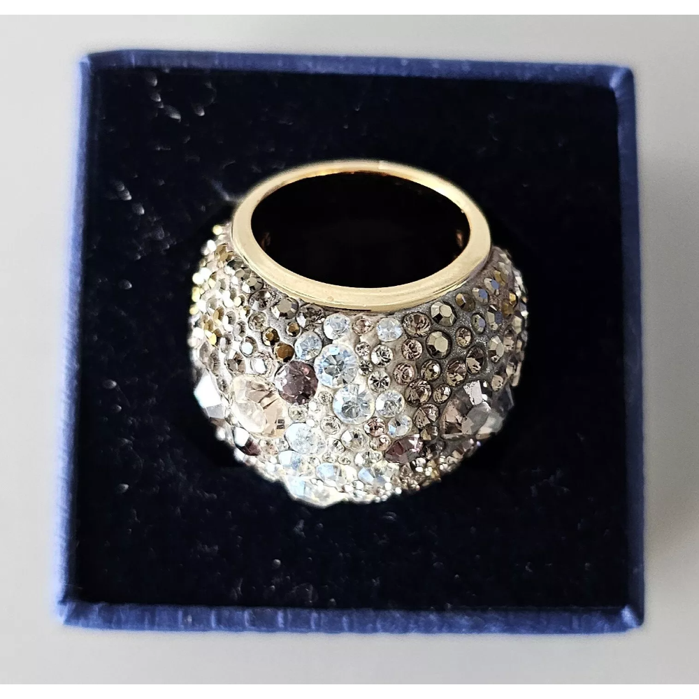 Gold ring with crystal embellishments on a black cushion