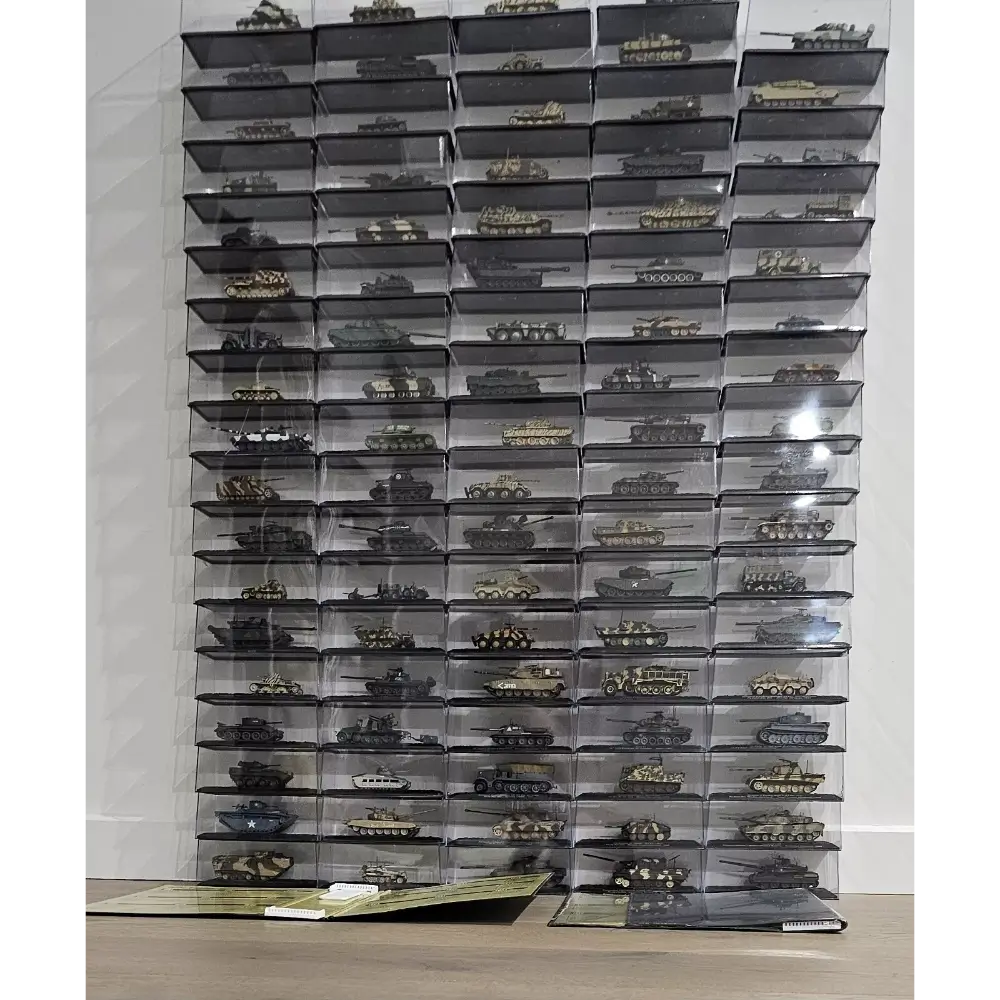 Collection of model tanks in clear display cases against a white wall.