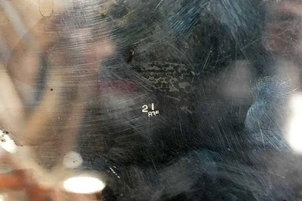 Close-up of a dark, scratched transparent surface with a small white handwritten marking reading '21 AGE'.