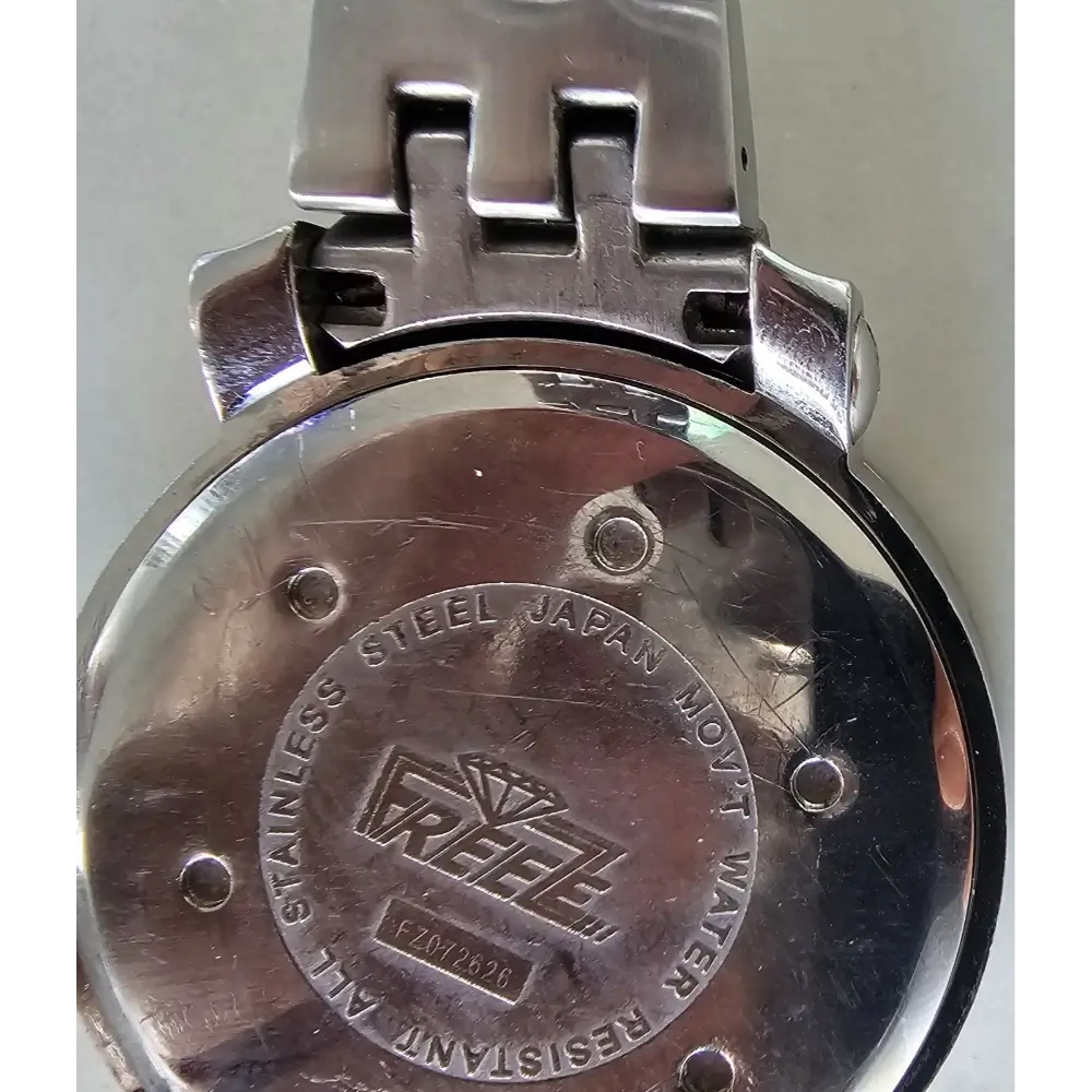Close-up of a metal watch case with branding and text.