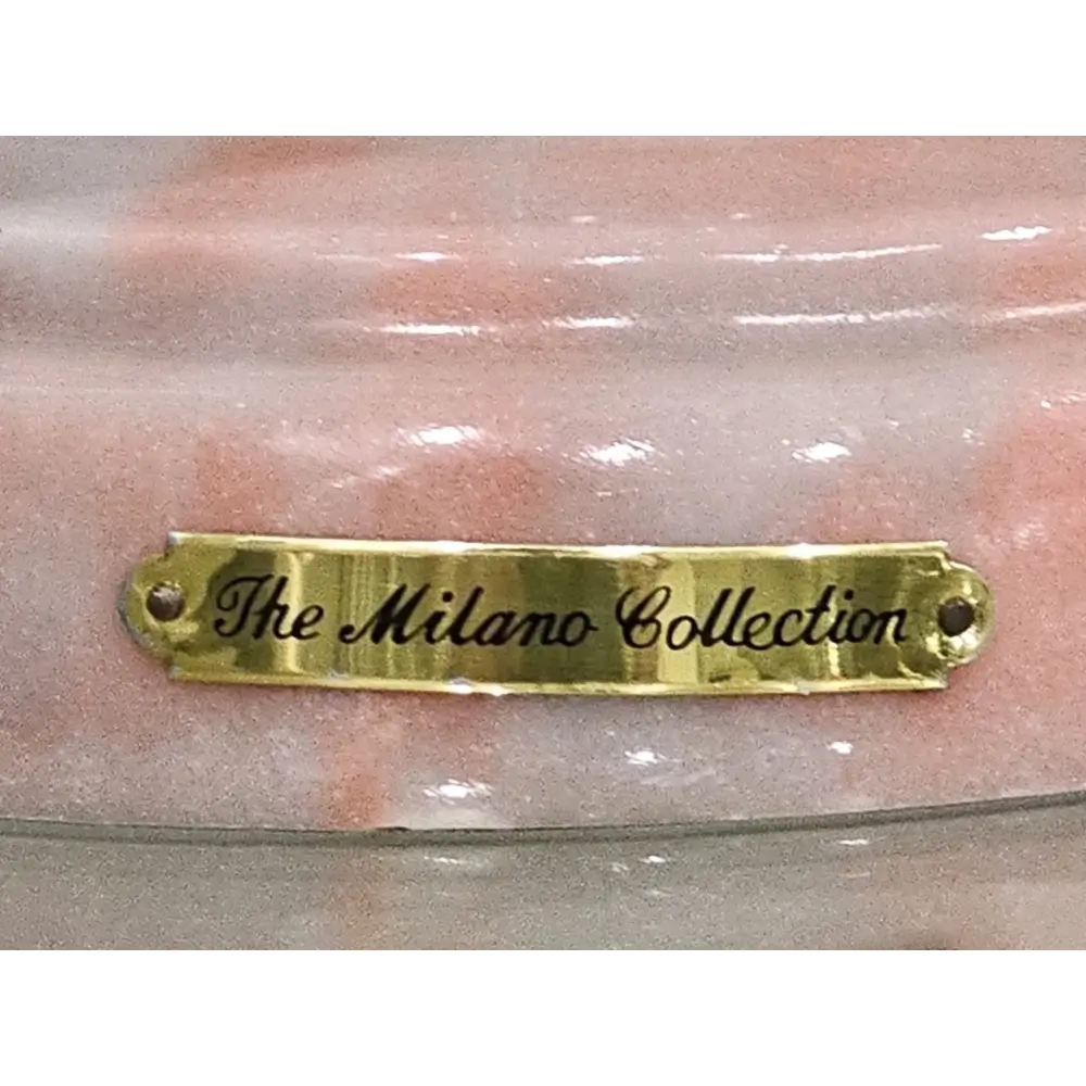 Gold plaque with 'The Milano Collection' text on a marble background
