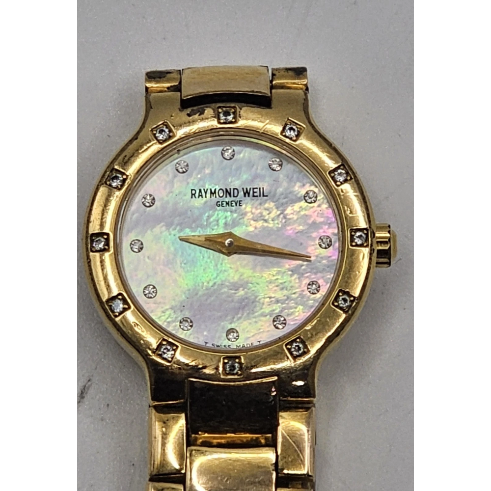 Gold watch with a decorative face on a gray background