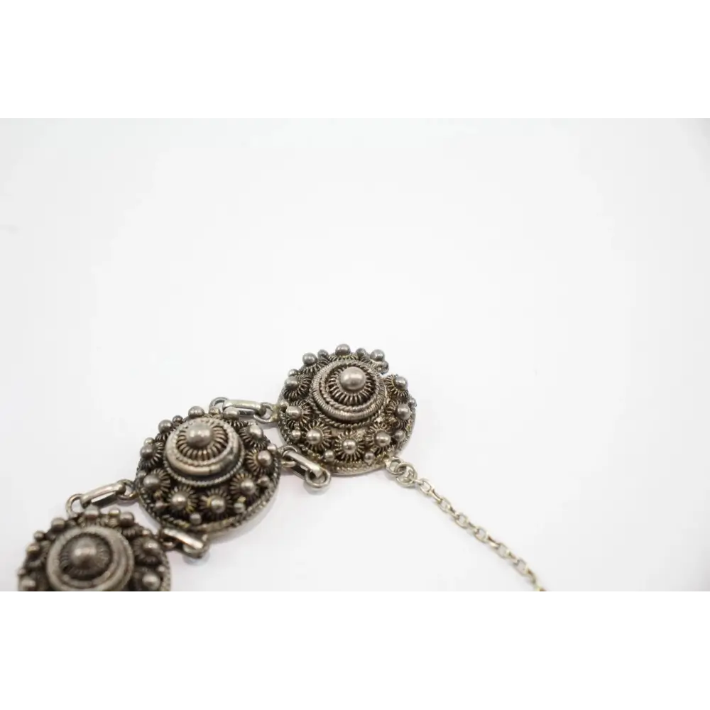 Silver bracelet with intricate designs on a white background