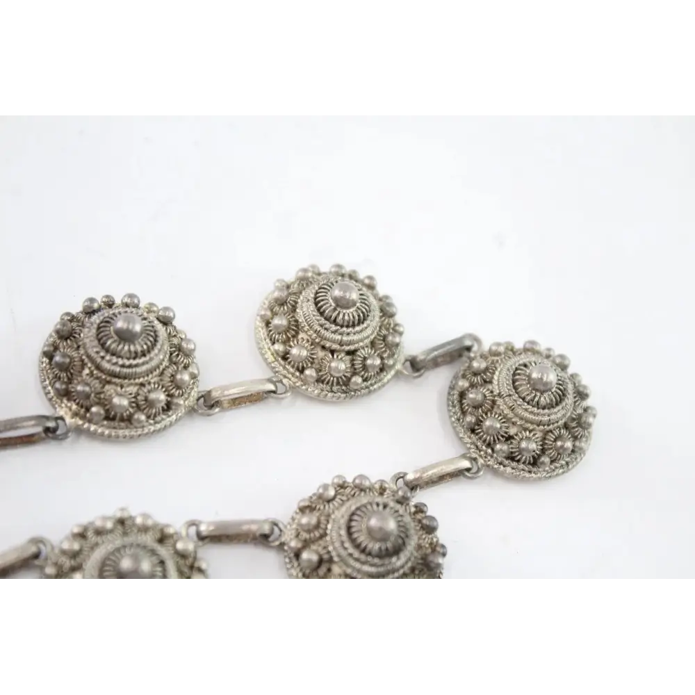 Silver necklace with intricate circular designs on a white background