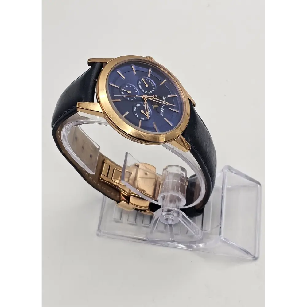 Watch with black strap and gold case on a clear stand