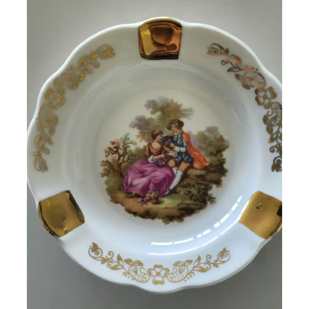 Decorative ceramic plate with gold accents and a painted scene