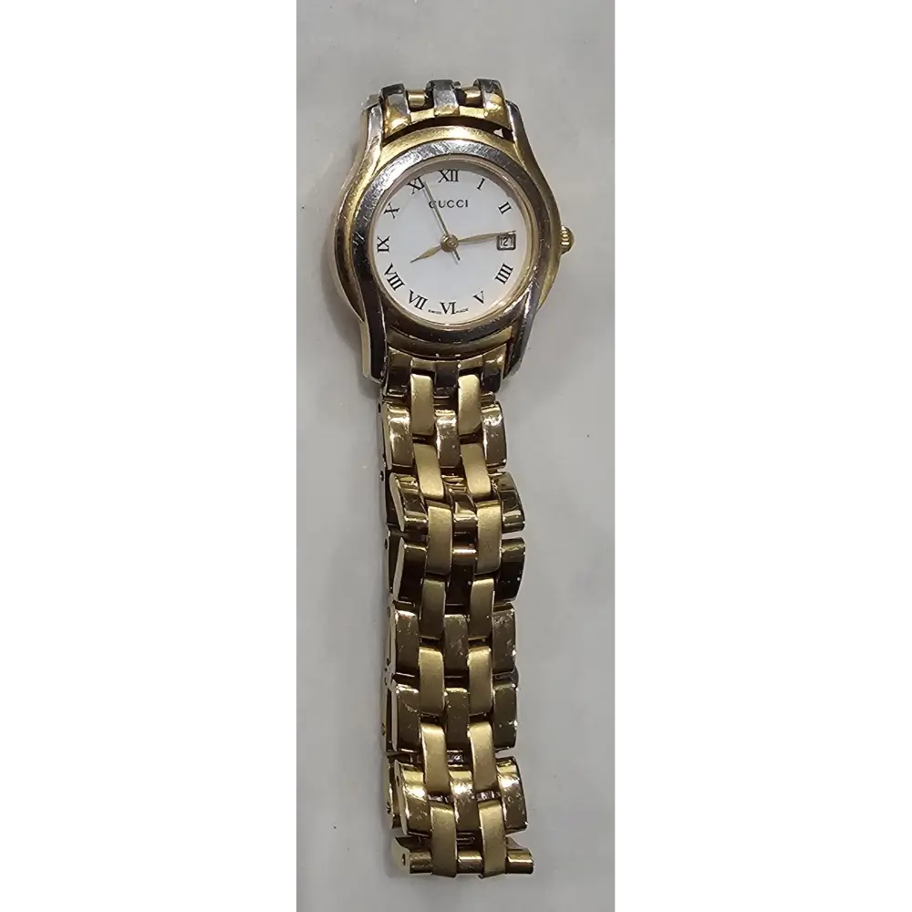 Gold watch with a white face on a gray background