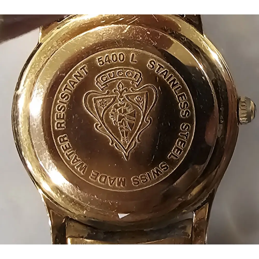Gold Gucci watch case with brand logo