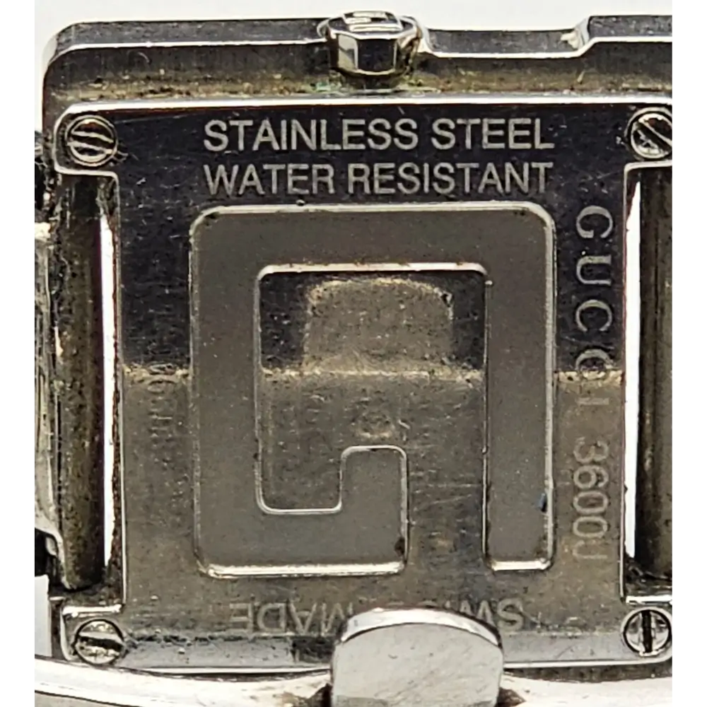 Close-up of a Gucci watch case with 'Stainless Steel' and 'Water Resistant' text.