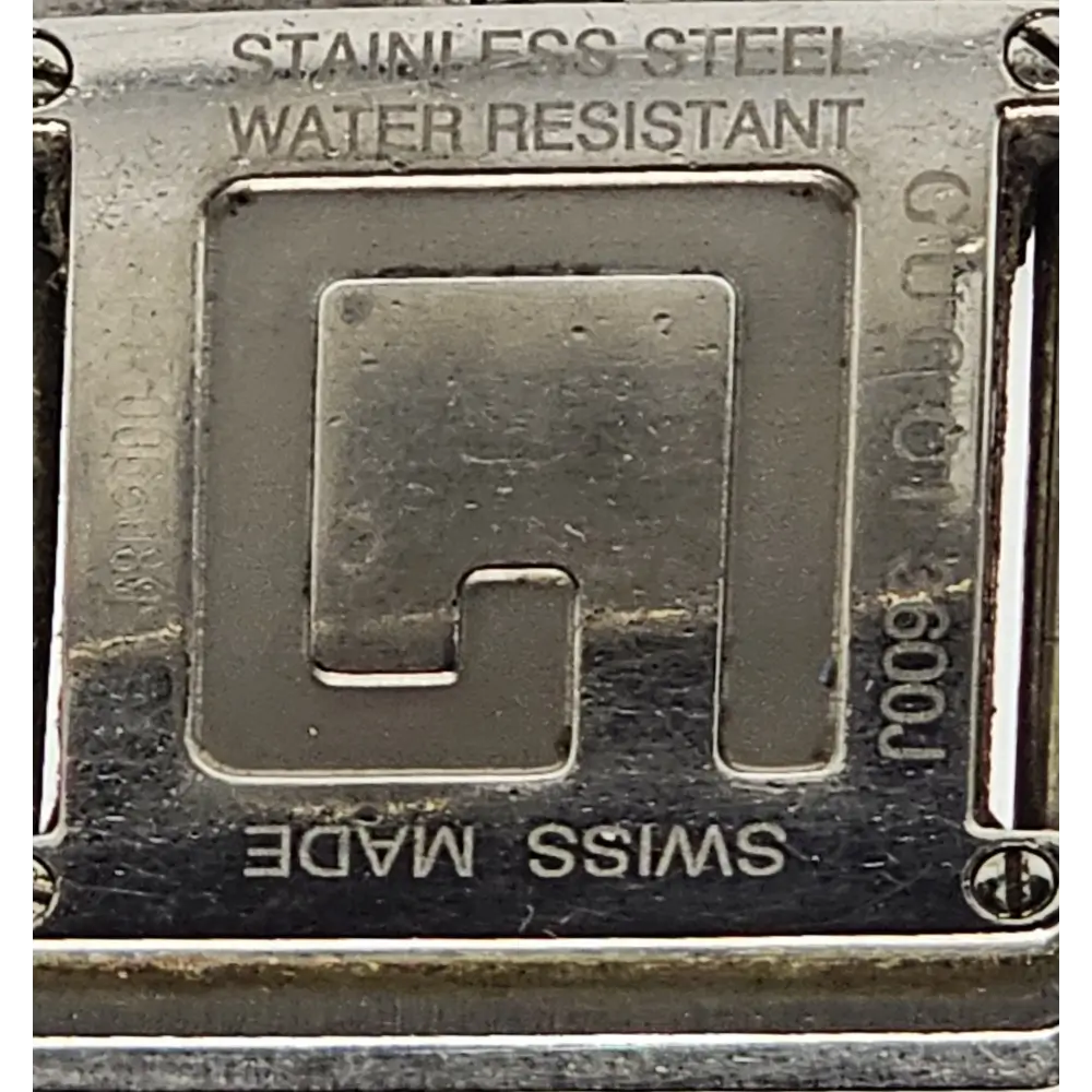 Close-up of a metal buckle with 'Stainless Steel', 'Water Resistant', and 'Swiss Made' text.