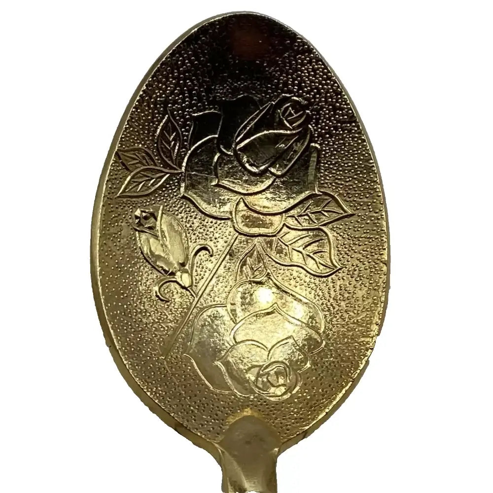 Gold spoon with rose embossing on a white background