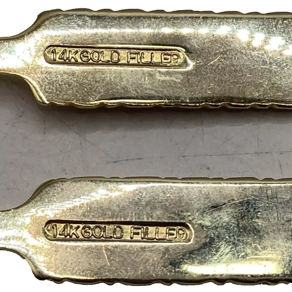 Two gold-filled metal objects with '14K Gold Filled' stamp on a metallic surface.