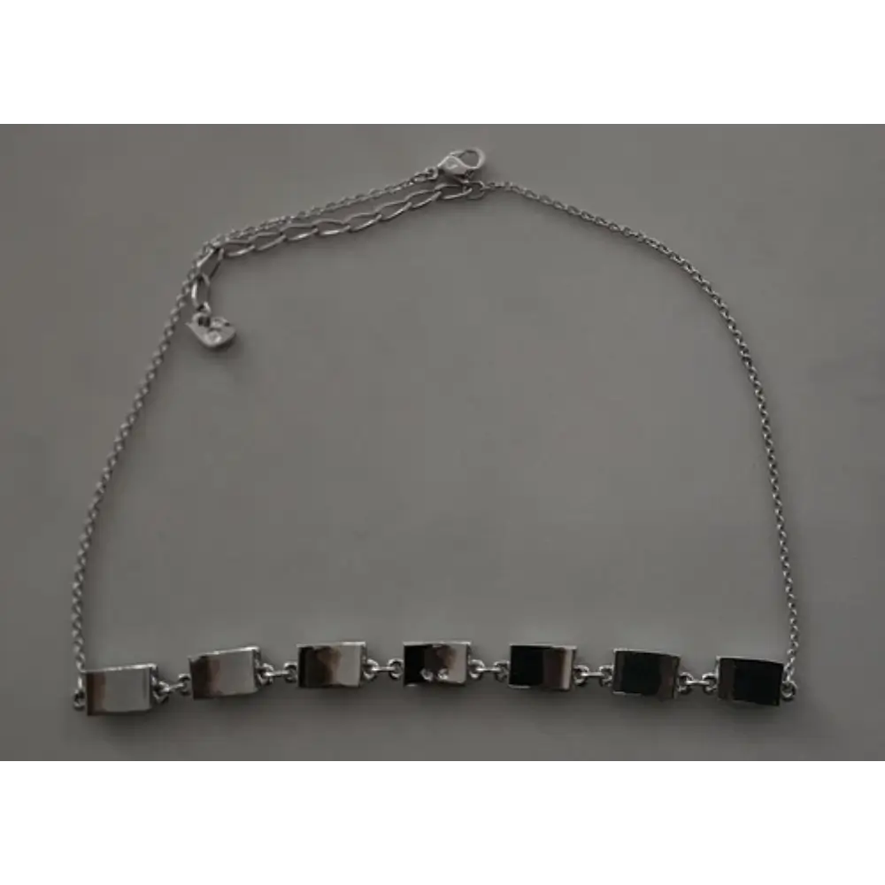 Silver bracelet with square links on a gray background