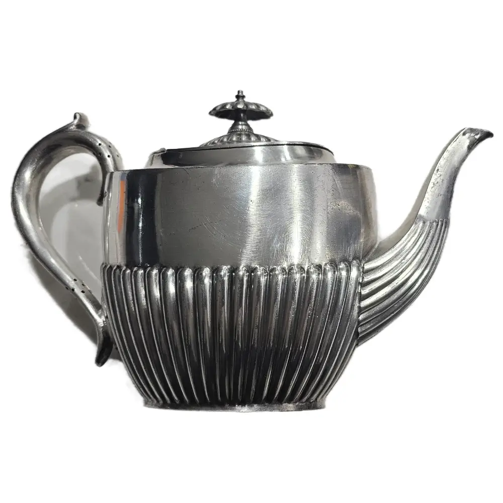 Silver teapot with ribbed design on a white background