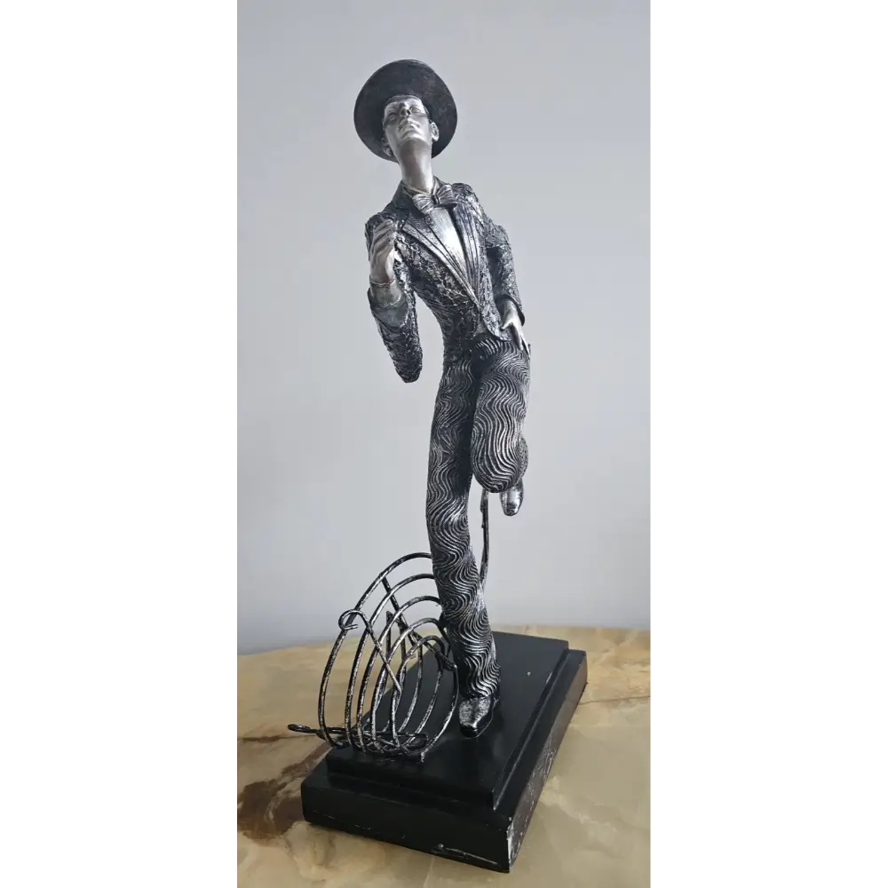 Statue of a person in formal attire with a hat on a wooden surface