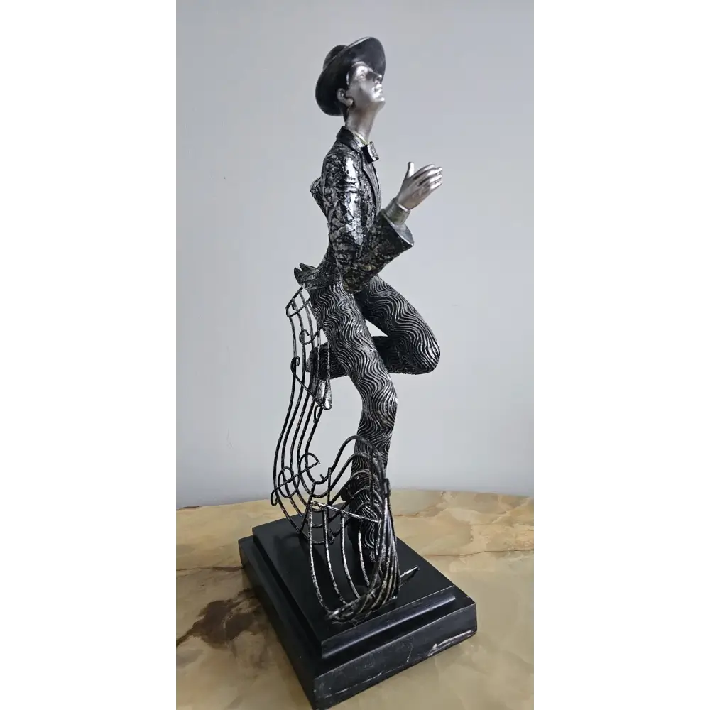 Statue of a person in a suit and hat on a wooden surface with a gray background