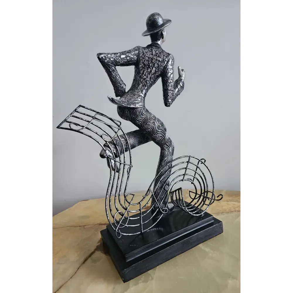 Decorative sculpture of a dancer with musical notes on a plain background