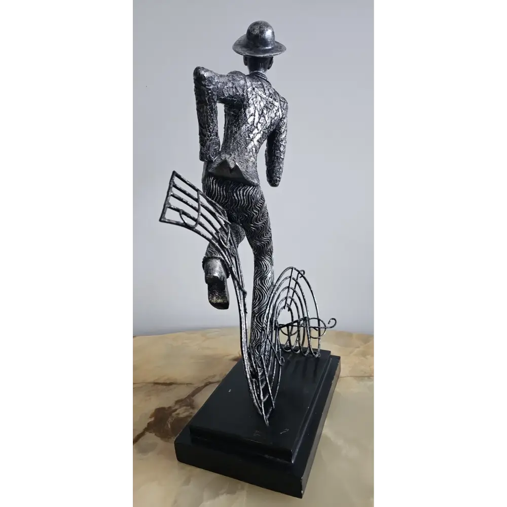 Metallic sculpture of a figure with a hat and musical instruments
