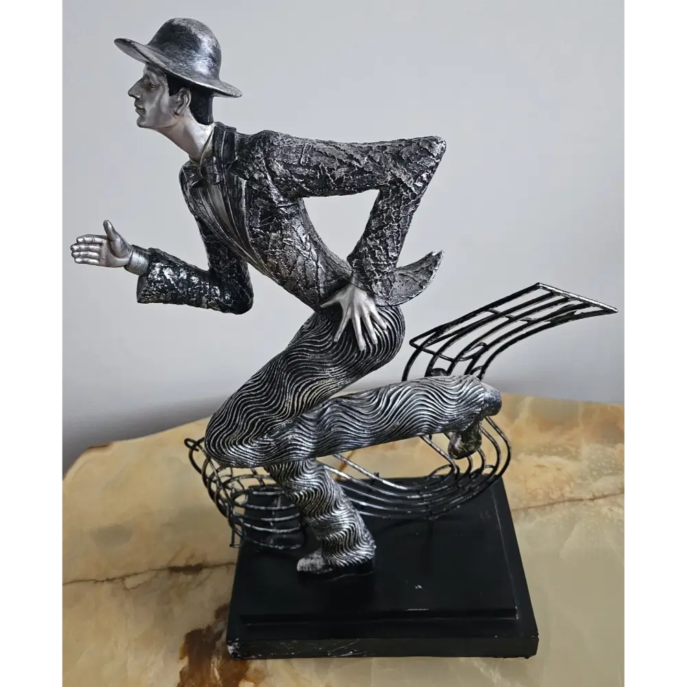Metallic sculpture of a person in dynamic pose with a music note