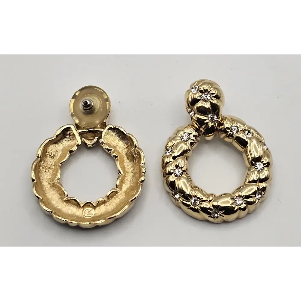 Gold hoop earrings with intricate designs on a light gray background