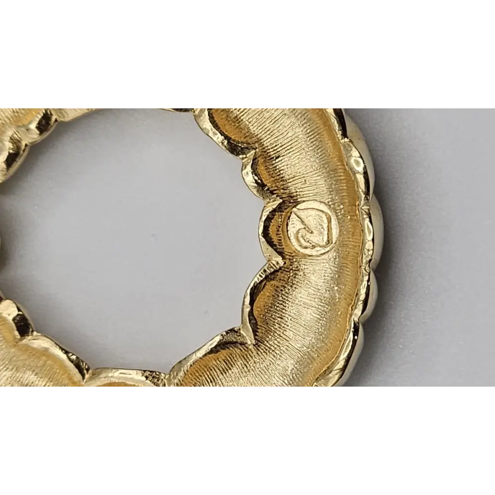 Gold ring with textured design on a light gray background