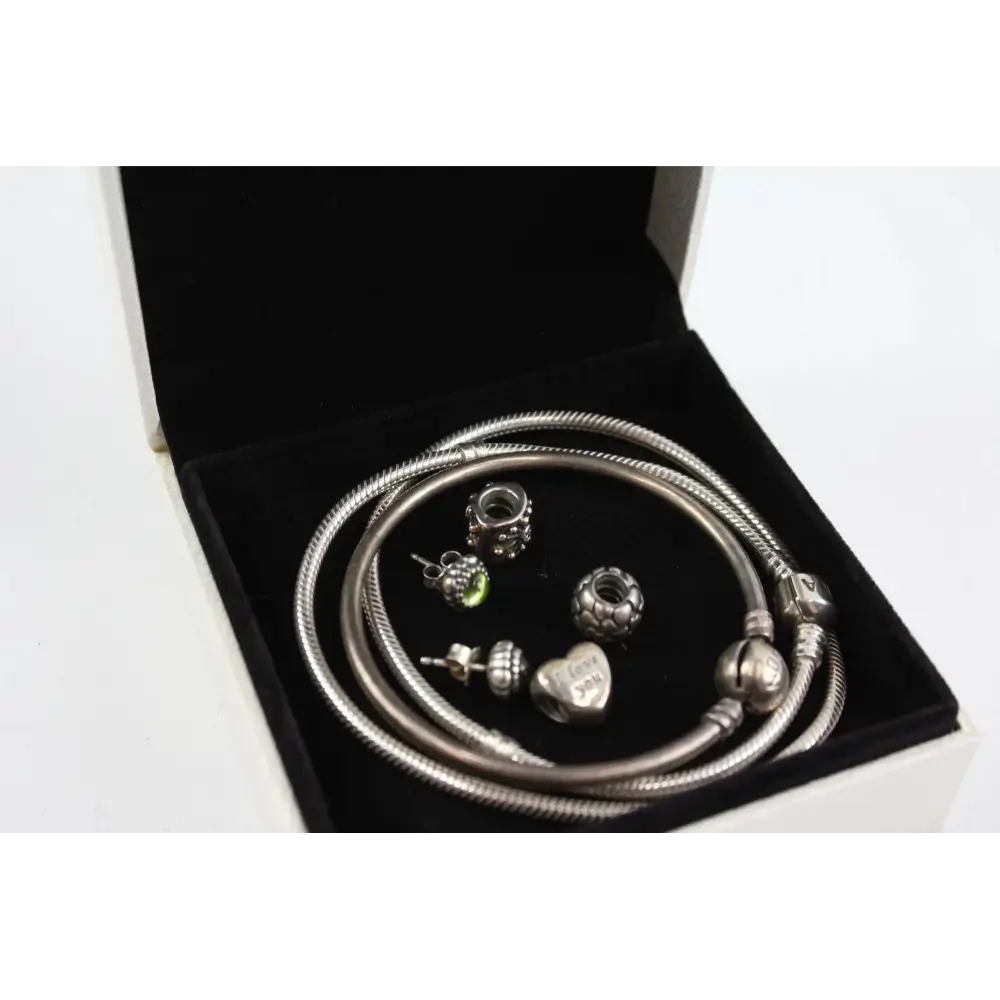 Silver jewelry set with snake chain bracelet and various charms in a black jewelry box.