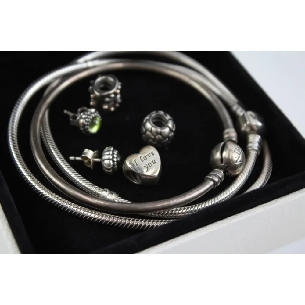 Silver jewelry set with bracelets and charms on a black background