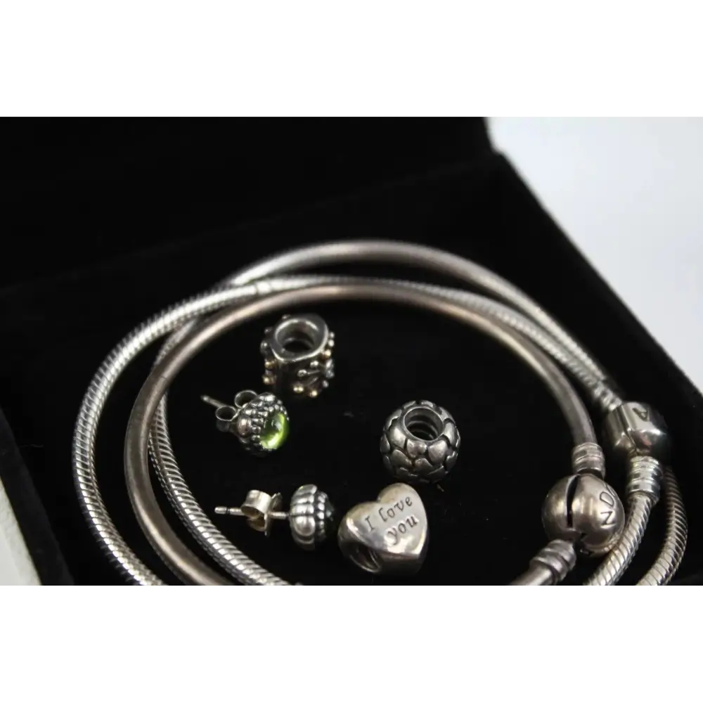 Silver bracelets and charms on a black background