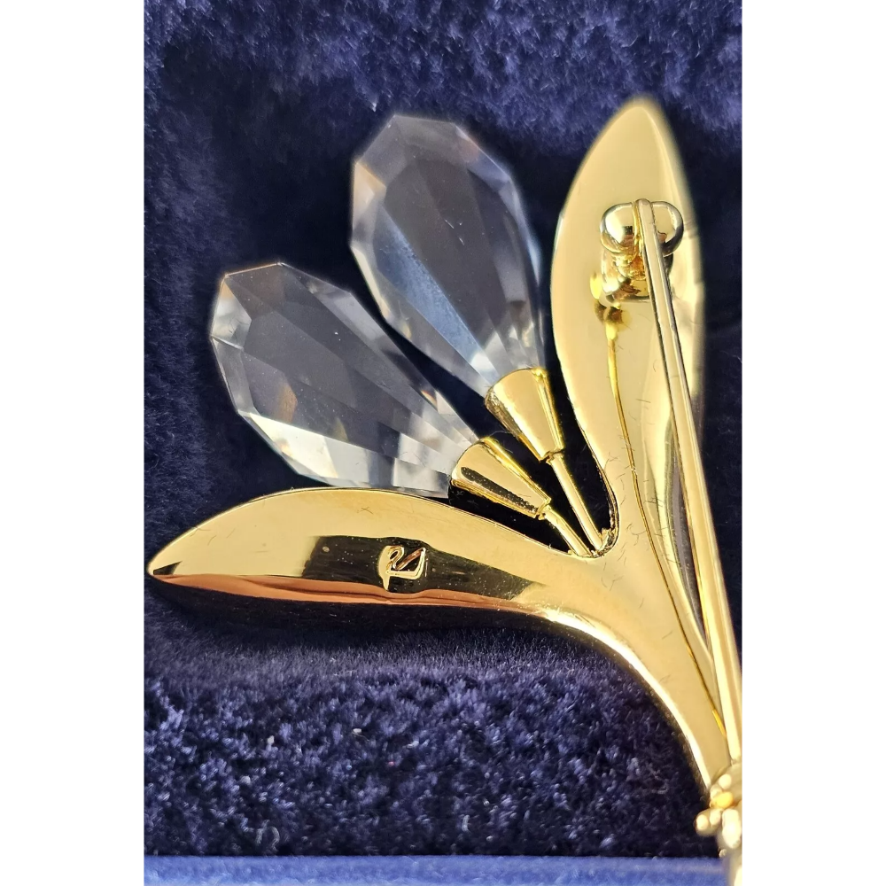 Gold brooch with clear crystal stones on a blue velvet background