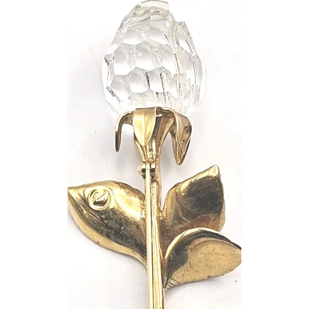 Gold rose brooch with a clear crystal on a white background