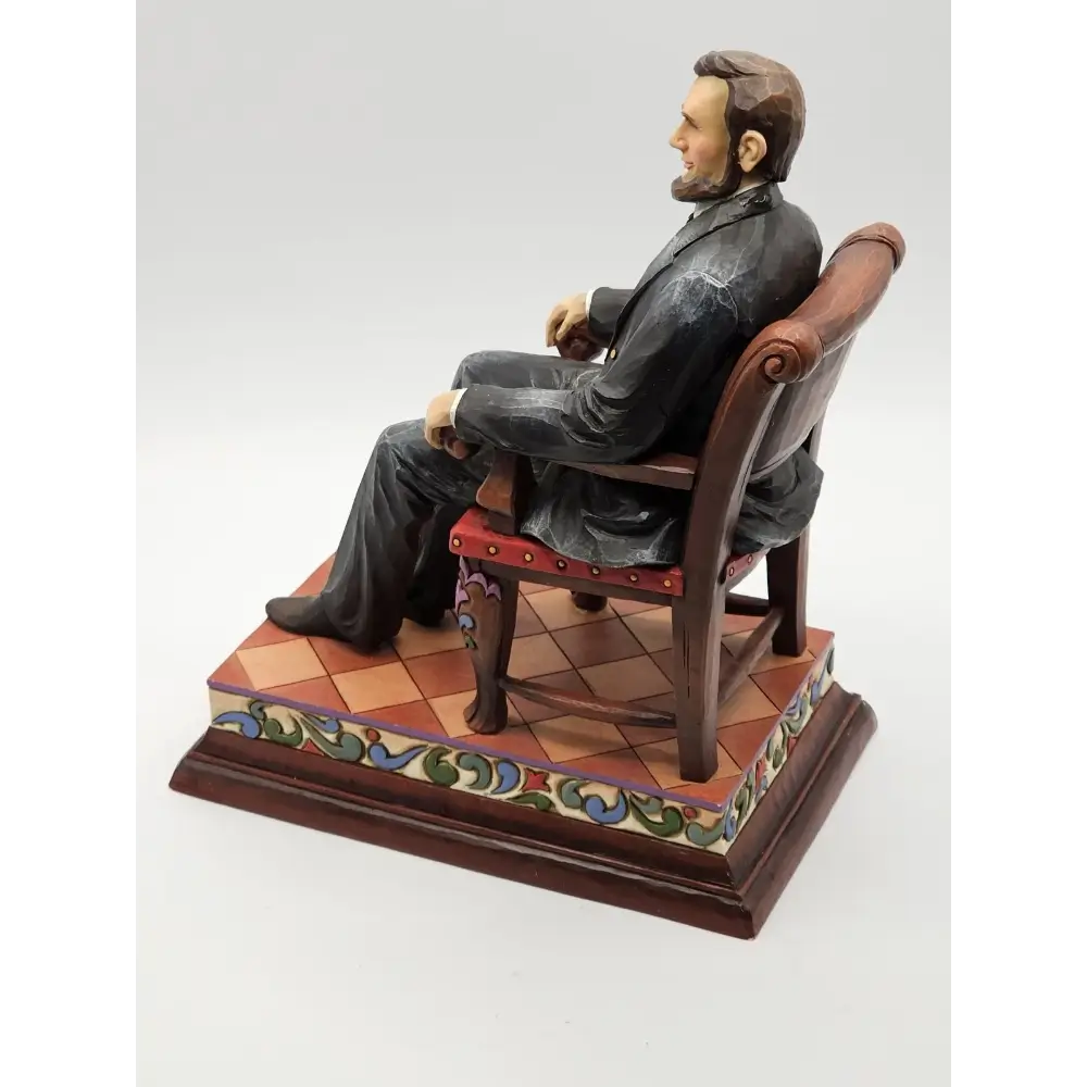 Statue of a man sitting on a chair with a decorative base