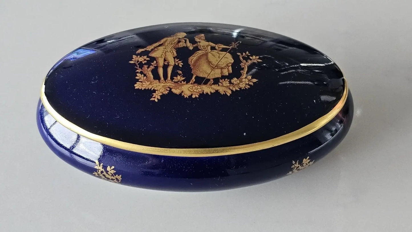 Blue powder compact with gold decorative elements on a gray background