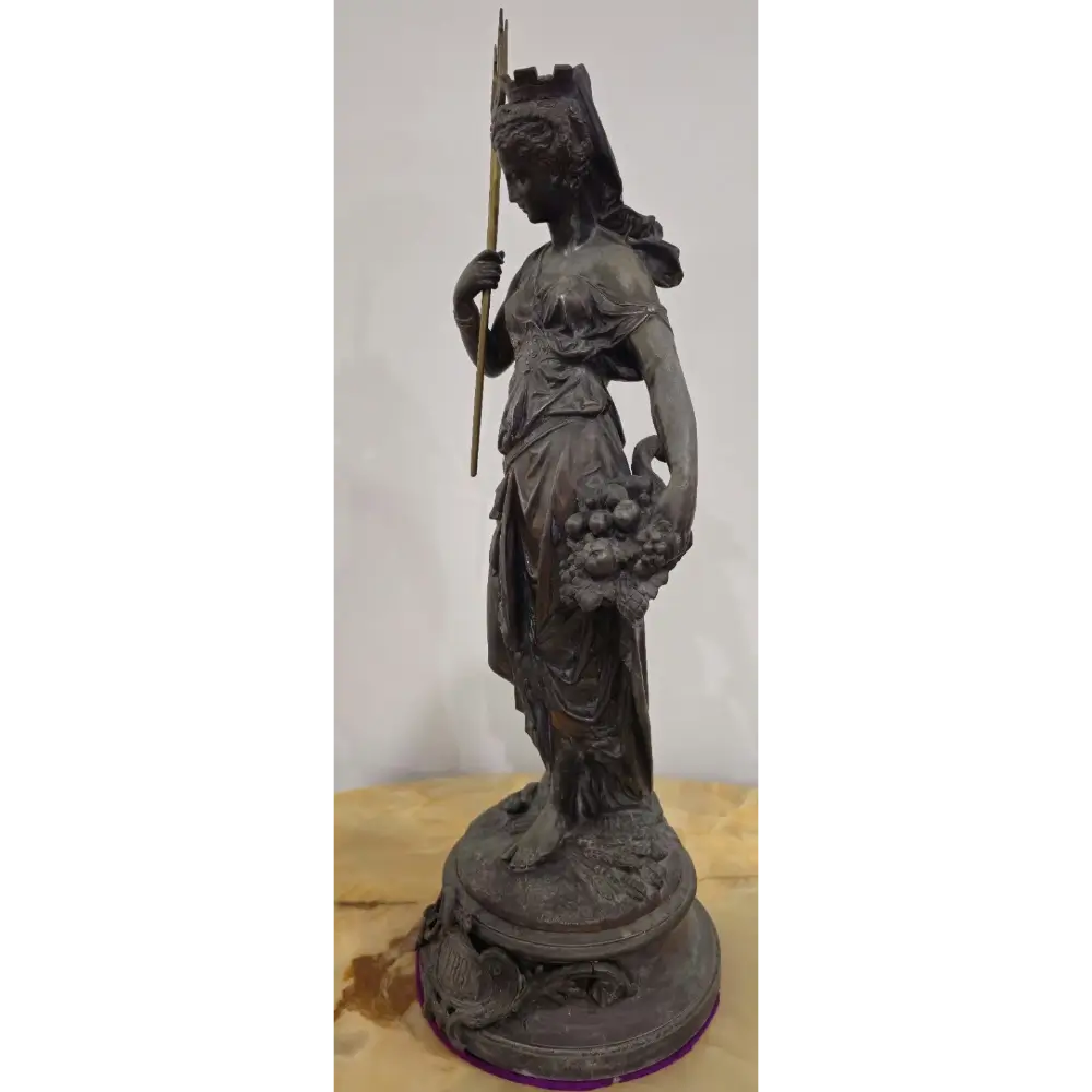 Bronze statue of a woman holding a spear and fruit on a wooden base with a white background