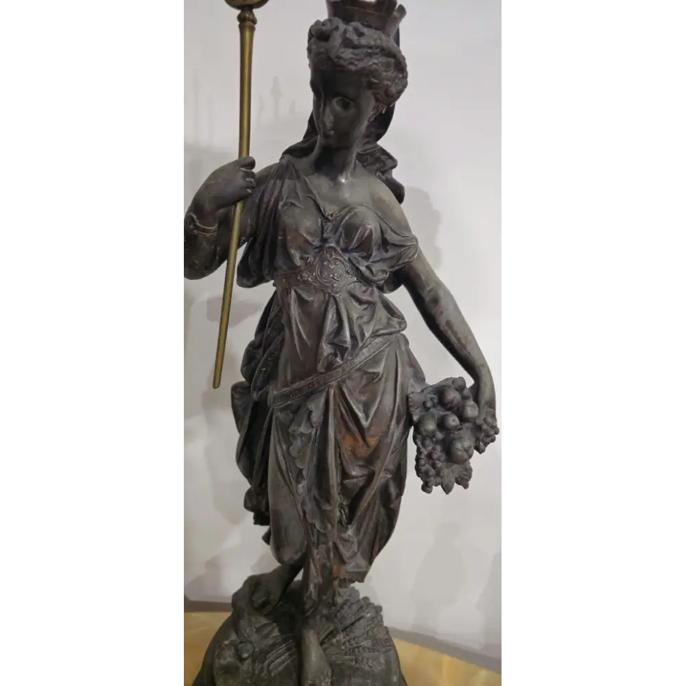Bronze statue of a woman holding a staff and basket
